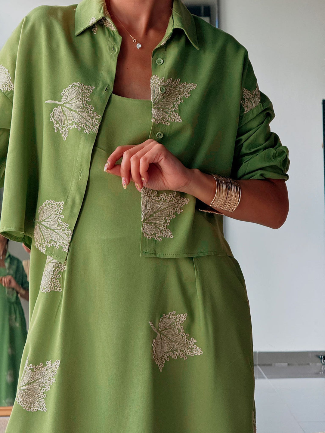Green outfit with leaf patterns worn by a person indoors.