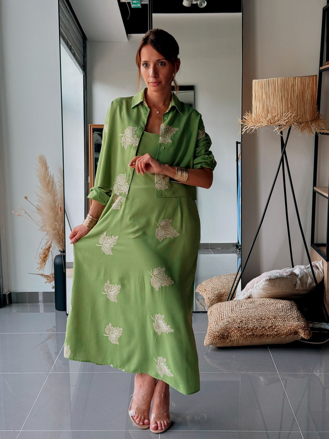Woman wearing a green dress with floral patterns in a modern interior setting.
