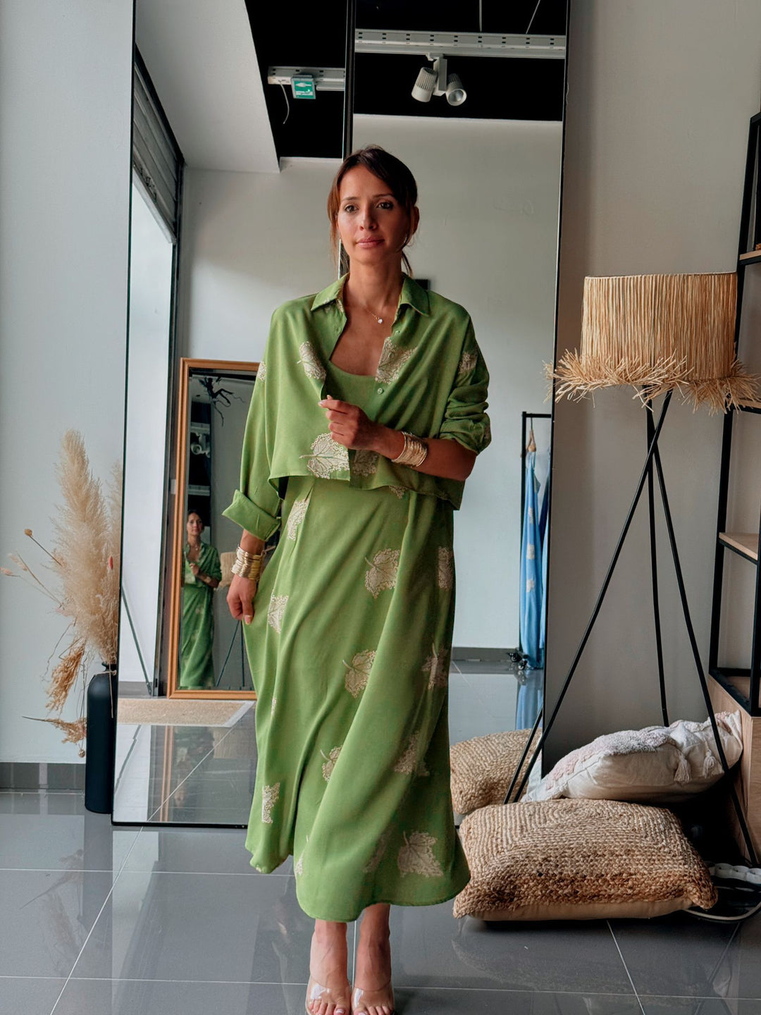 Woman in a green dress standing in a modern interior setting with decor elements.