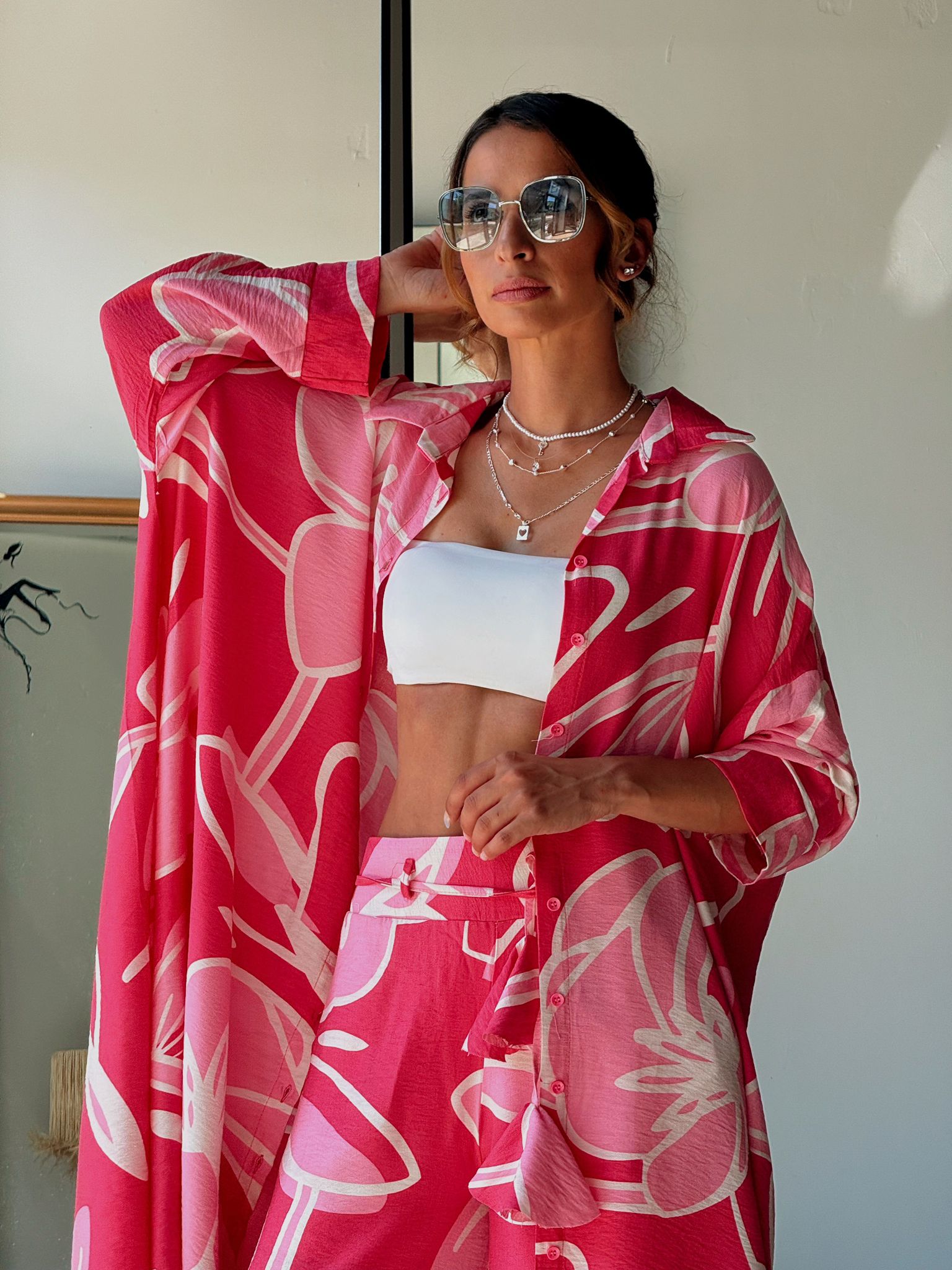 Woman wearing a pink floral kimono over a white top, standing indoors.