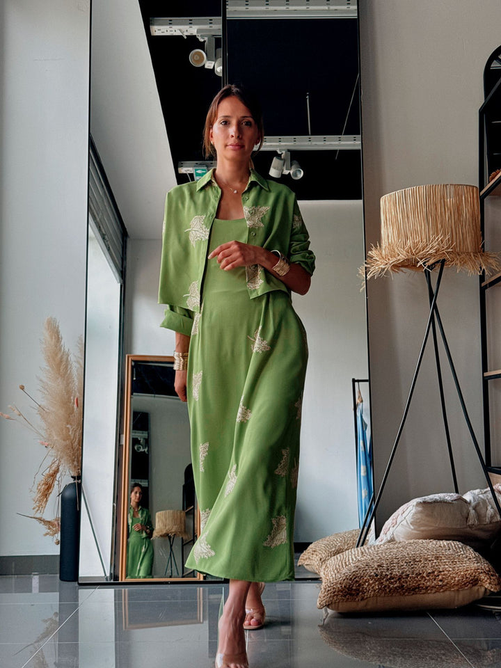 Woman in a green dress standing in a modern interior setting with decor elements.