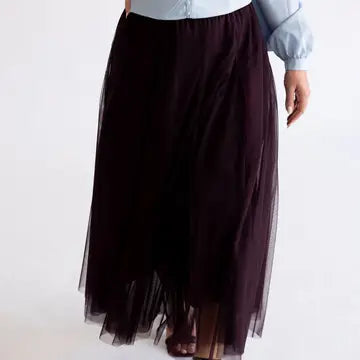 A dark plum tulle midi skirt worn by a model, paired with a light blue long-sleeve top, shown against a plain white background.