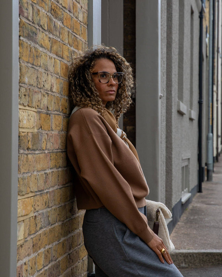 Woman leaning against a brick wall in an urban setting