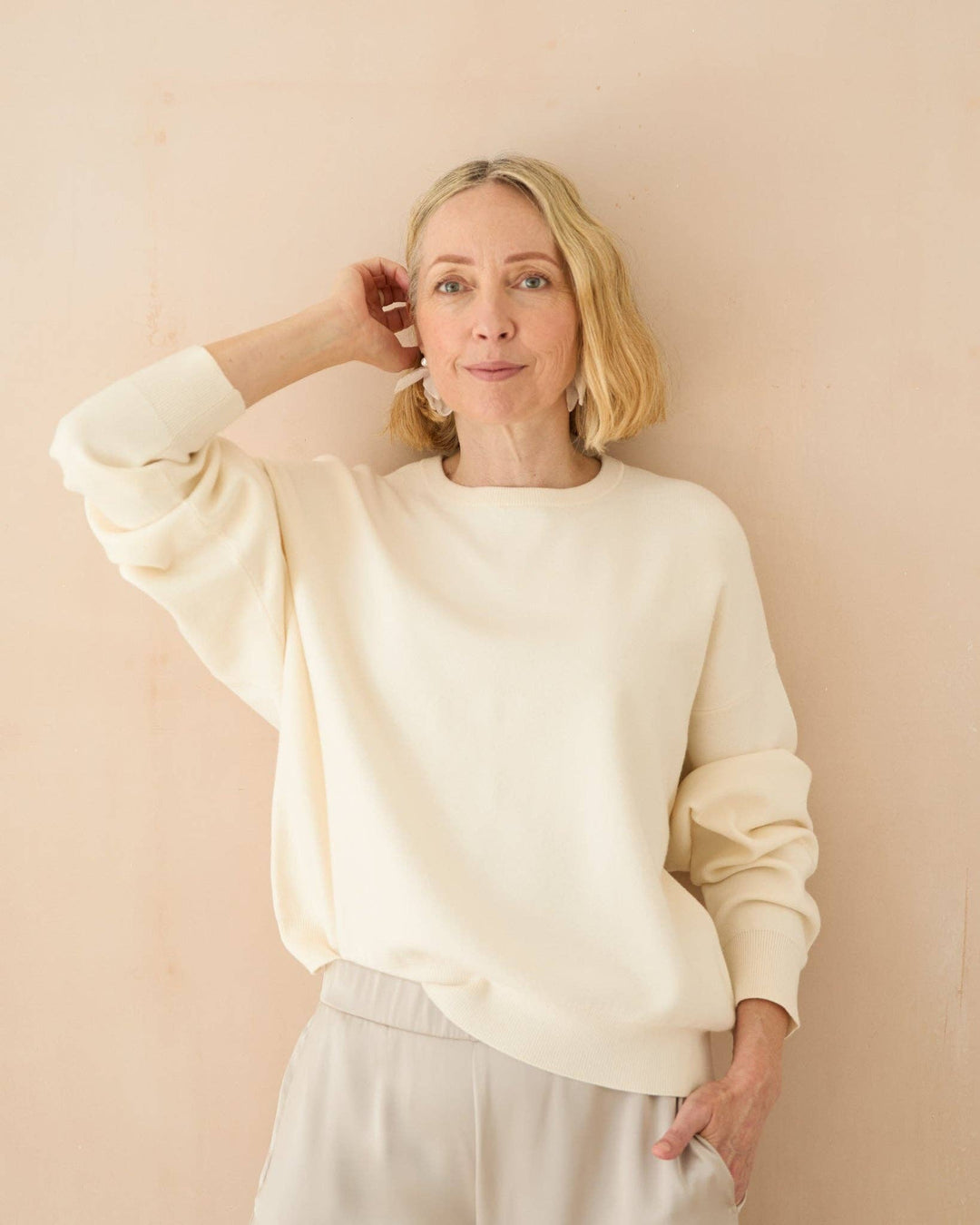 Woman wearing a cream-colored sweater against a beige background