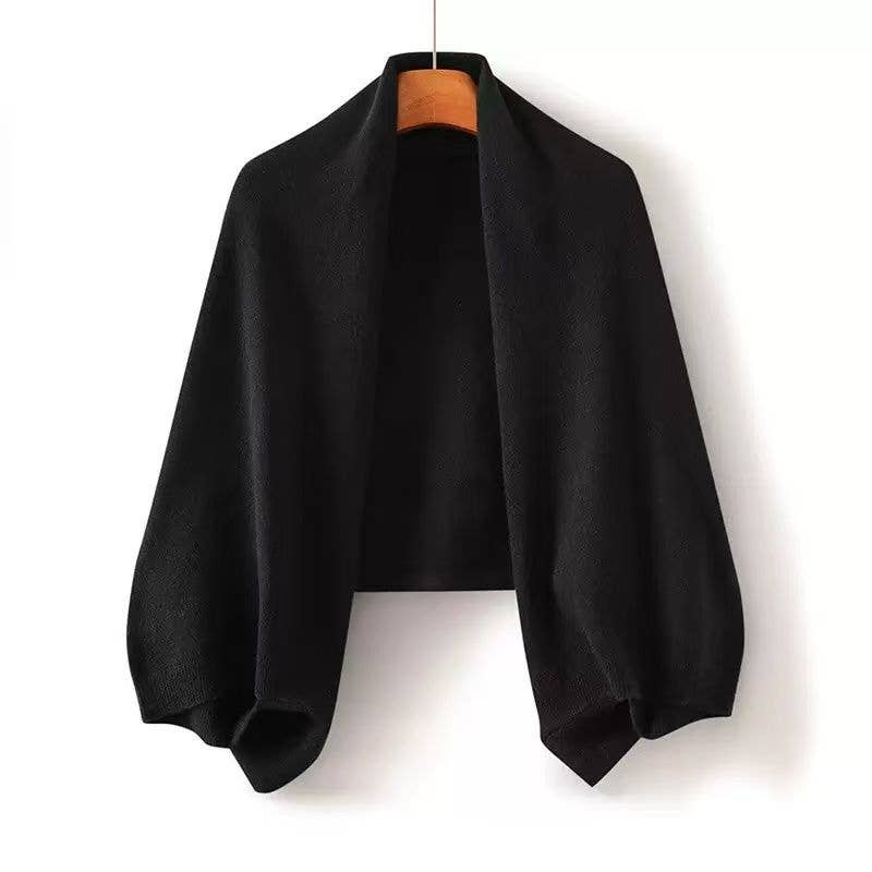 Black poncho on a hanger against a white background