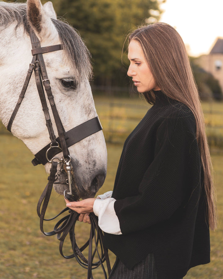 Woman standing next to a white horse in an outdoor setting