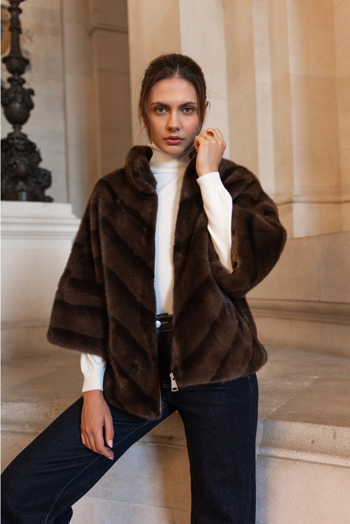 Woman wearing a brown fur coat in an indoor setting with columns.
