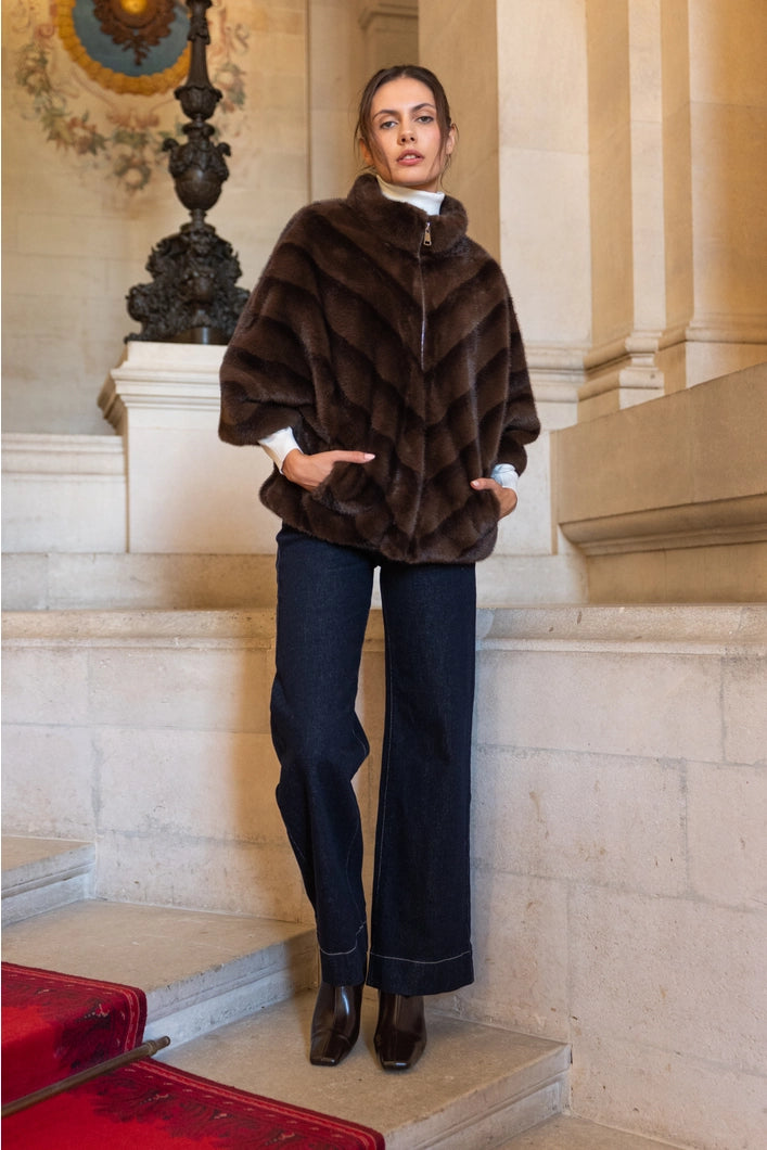 Woman wearing a brown fur coat and dark jeans standing on a staircase.