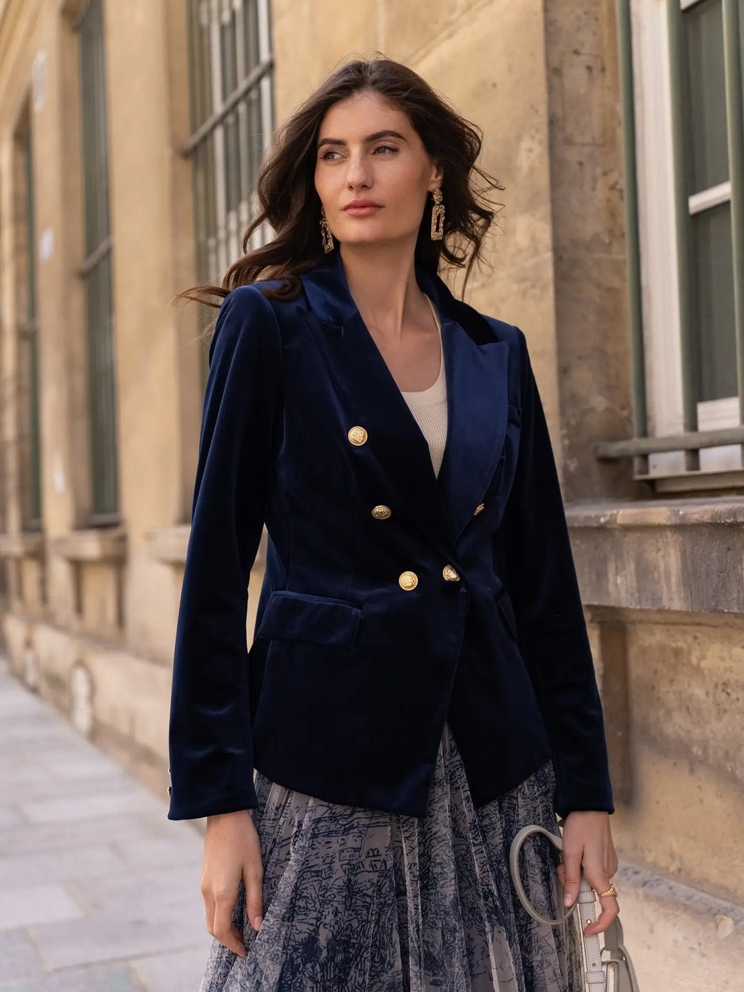 Woman wearing a navy blazer with gold buttons in an urban setting