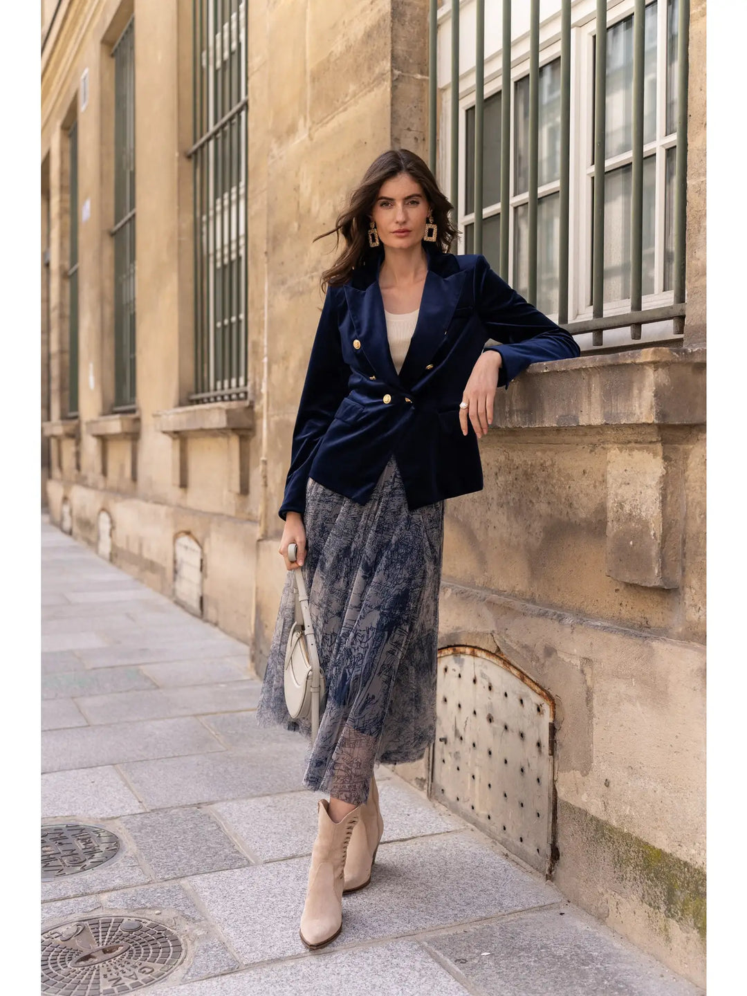 Woman in a stylish outfit standing against a stone building.