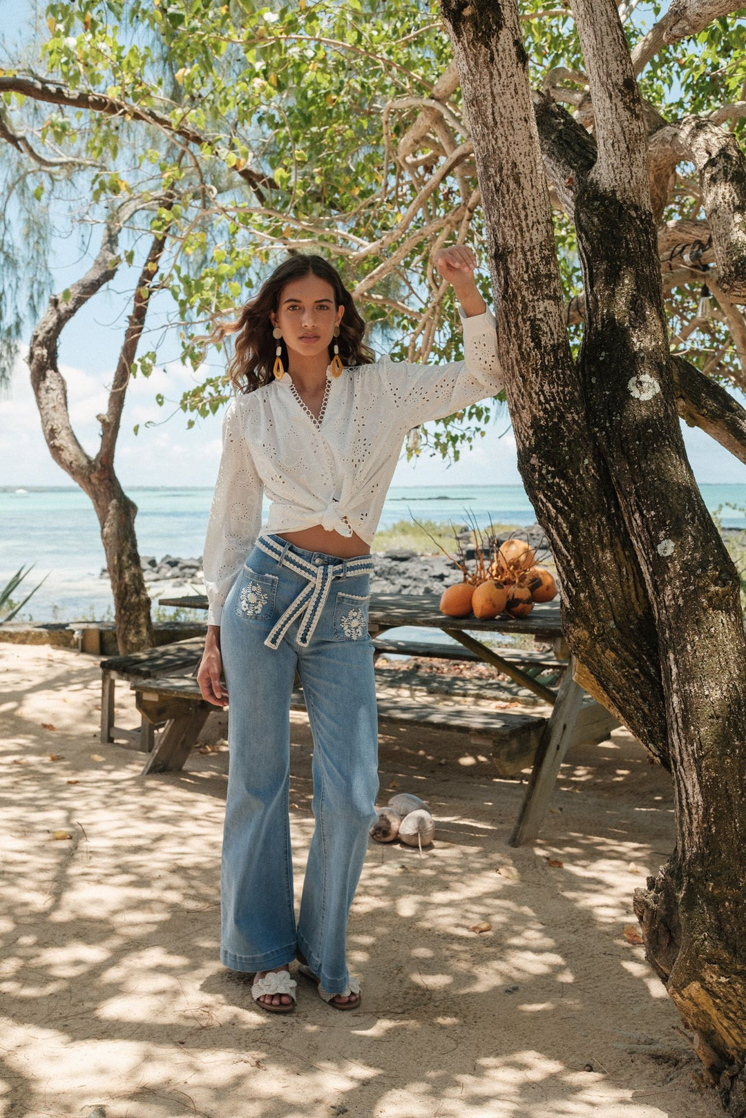 Woman standing outdoors near a tree with ocean view