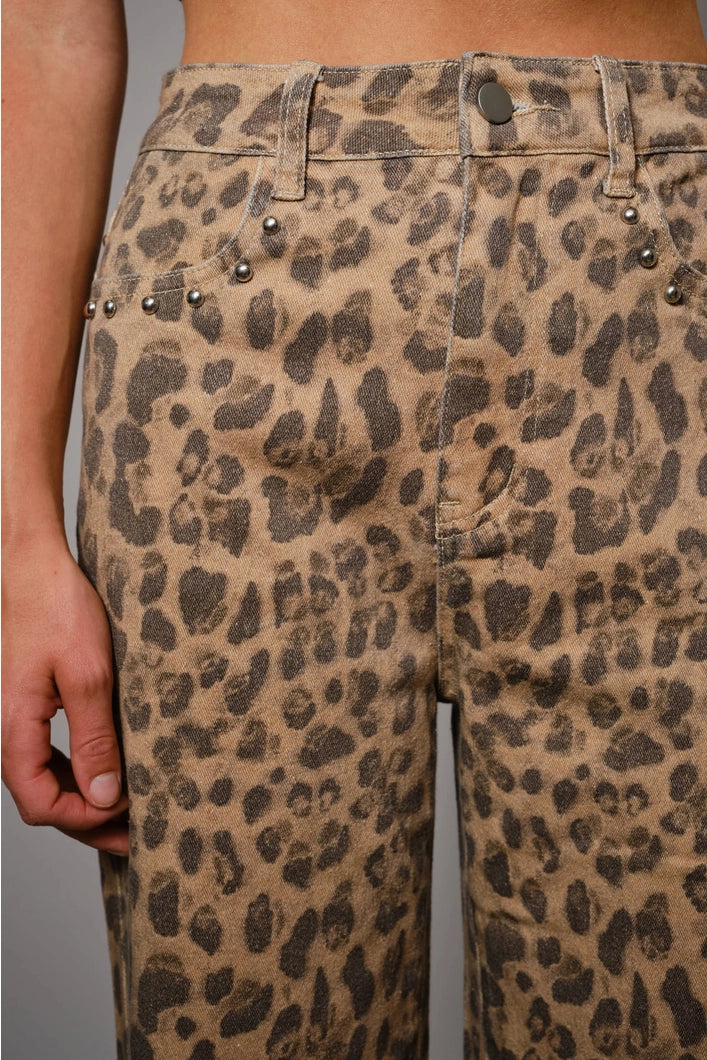Leopard print pants with decorative buttons on a plain background