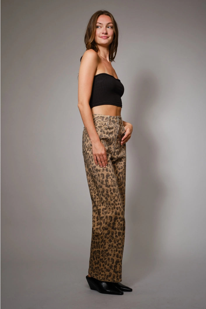 Woman wearing leopard print pants and a black top against a gray background