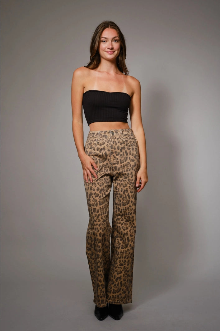 Woman wearing a black strapless top and leopard print pants against a gray background