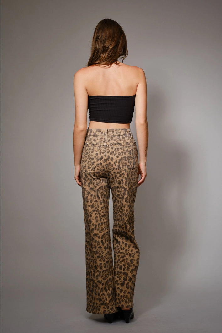 Woman wearing a black strapless top and leopard print pants against a gray background