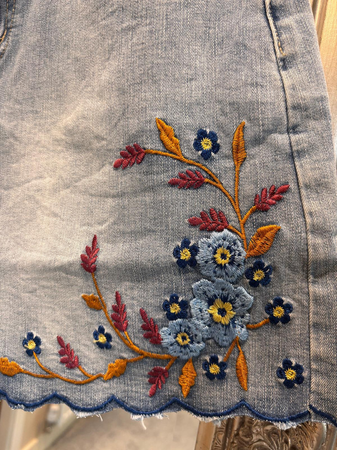Embroidered floral design on a denim fabric background